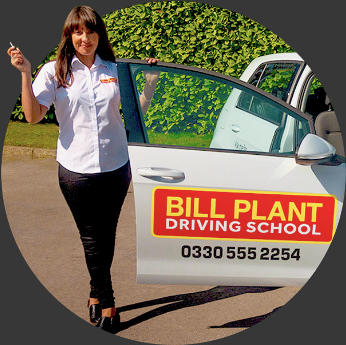 A female driving instructor stood in front of a Bill Plant Driving School car.